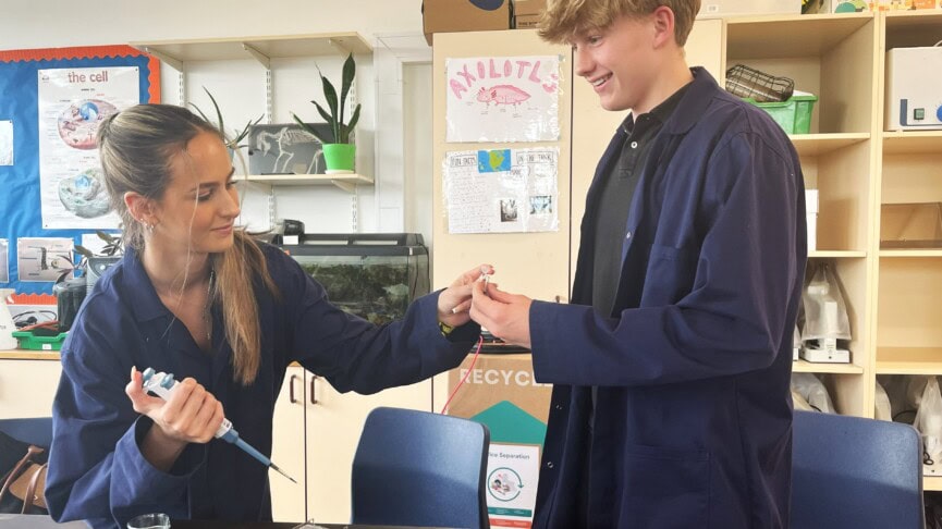 a male and female student in blue lab coats take a sample