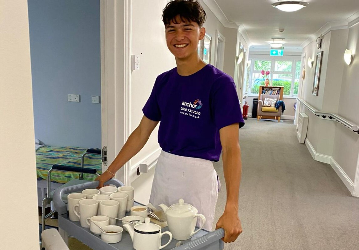 student delivers tea tray in corridor of a care home