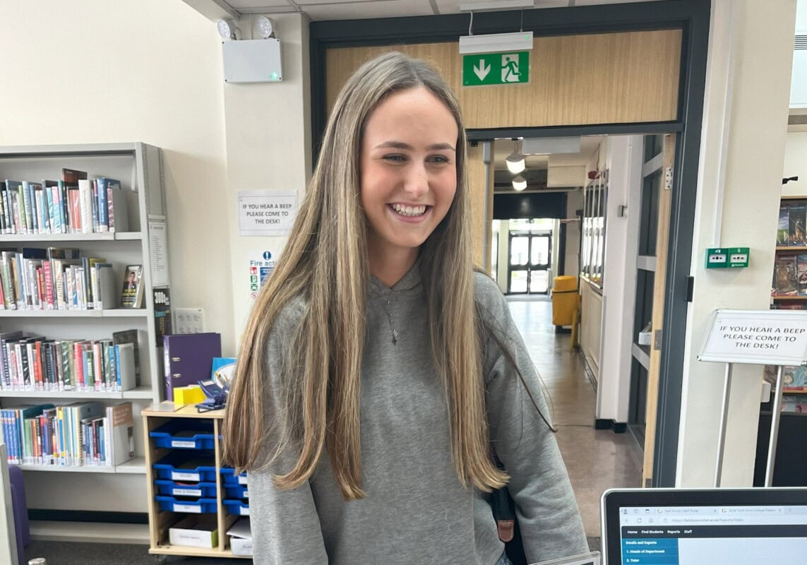 Latie smiling as she talks to a library assistant in the LRC