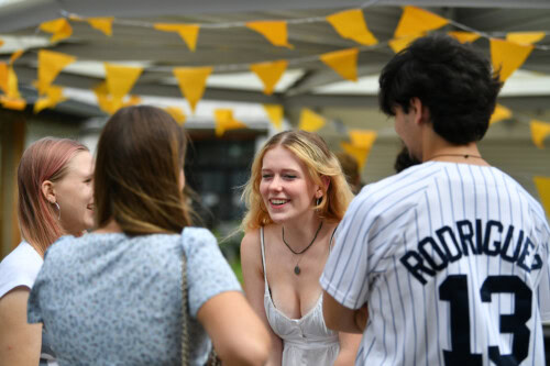 Group of students celebrating happy exam results 2024 under yellow bunting
