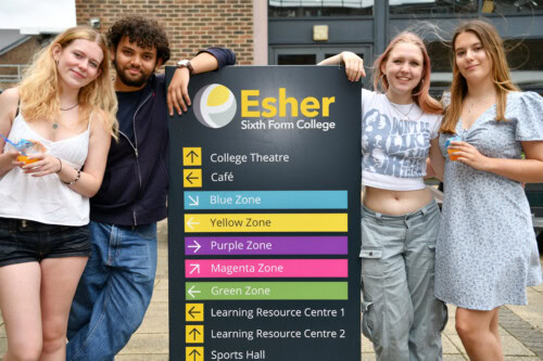 Group of 4 students leaning on Esher directional sign