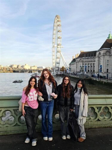 Four female students standing on front of the London eye