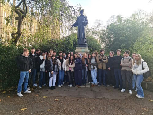 Large group of students standing in front of a statue