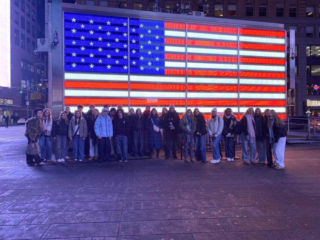 group of students standing in front of American Flag Timesquare