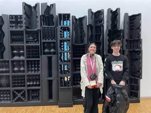 two students standing in front of installation in a gallery