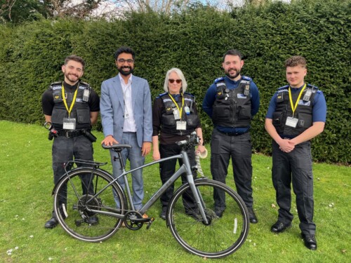 staff member standing with his bike and the police on the college grounds