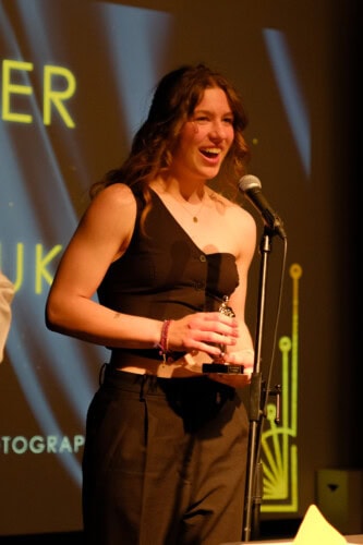 An excited female student standing on stage making a speech